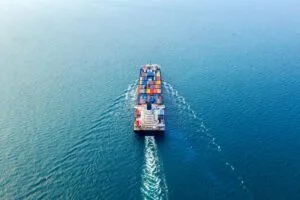 Luftaufnahme eines Containerschiffs auf dem Meer, das die globalen Lieferketten-Trends 2024 und die Bedeutung der Versandlogistik symbolisiert.